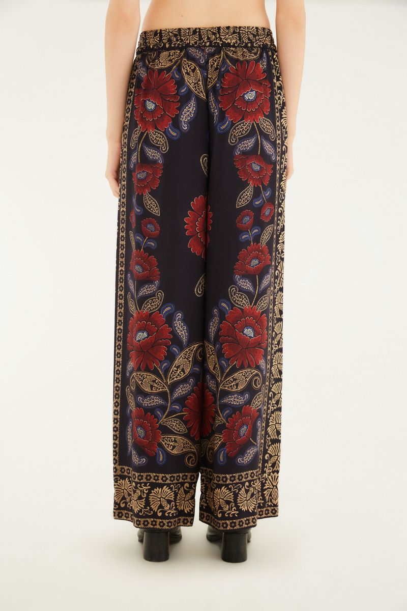 Imagen trasera del pantalón estampado destacando el patrón floral y el estilo palazzo.