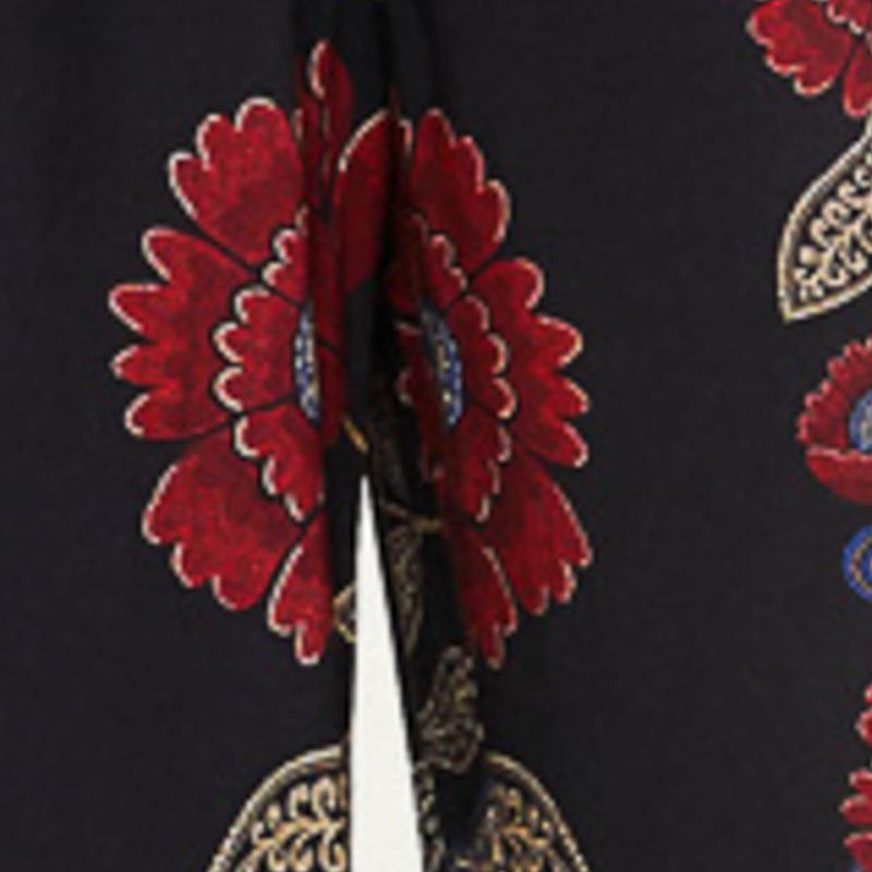 Close-up del detalle del estampado floral en el pantalón, mostrando los elementos en rojo y dorado sobre fondo negro.