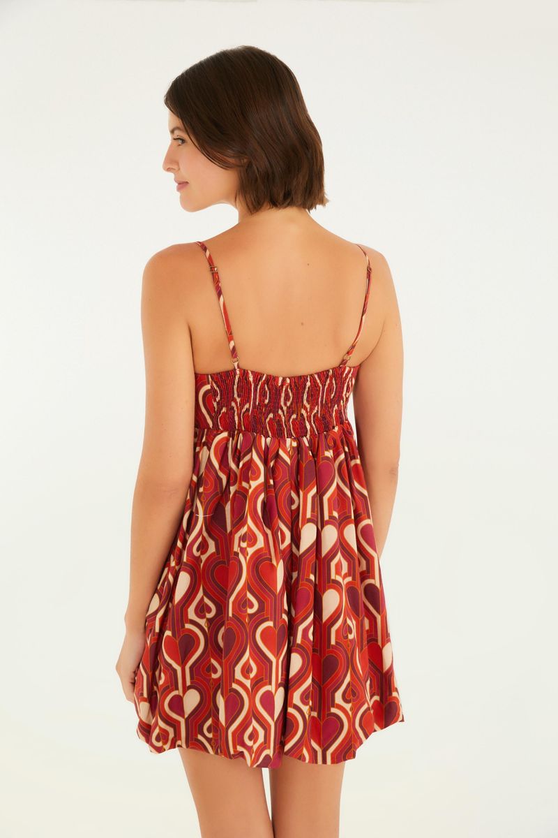 Vista trasera del vestido corto estampado con patrón geométrico en tonos rojos y blancos, mostrando el ajuste elástico en la espalda.