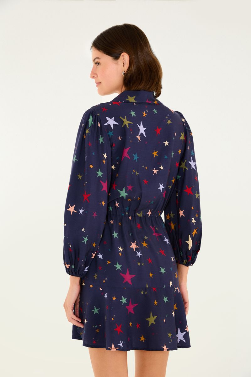 Vista lateral del vestido corto con estampado de estrellas multicolores, destacando el ajuste en la cintura.