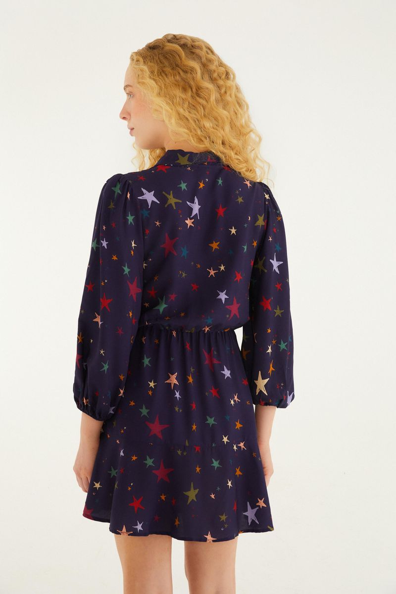 Vista trasera del vestido corto con estampado de estrellas multicolores, mostrando el ajuste en la cintura.