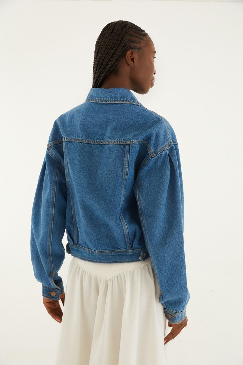 Vista trasera de la chaqueta cropped en denim azul con mangas largas.