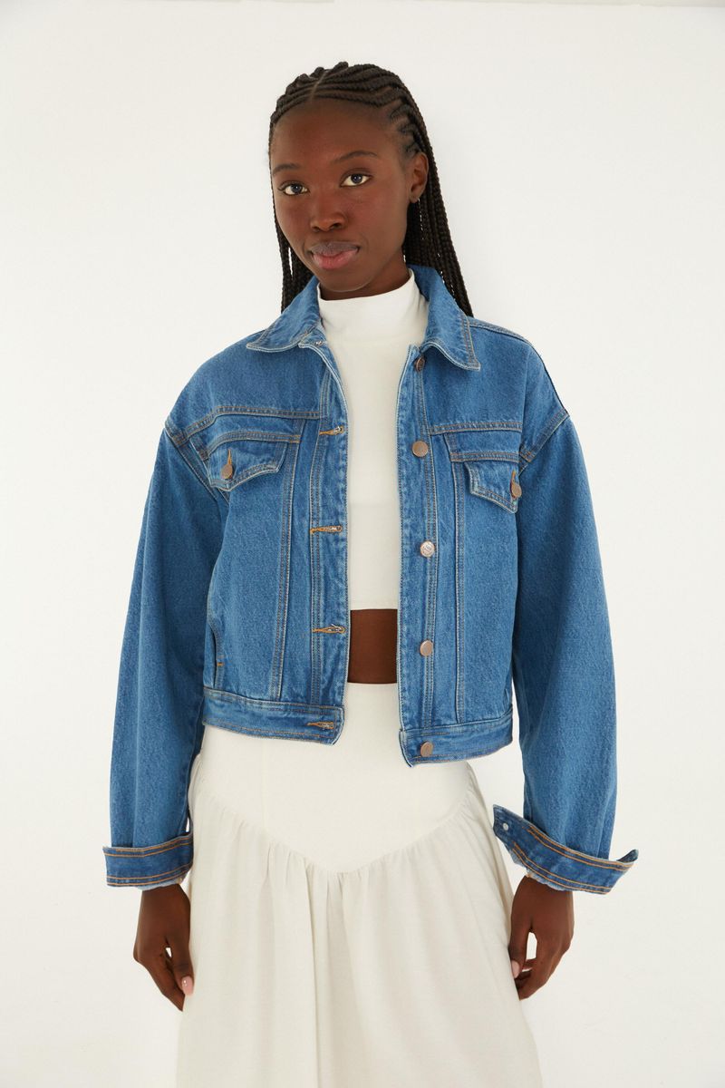 Chaqueta cropped en denim azul con mangas largas y cierre con botones, vista frontal.
