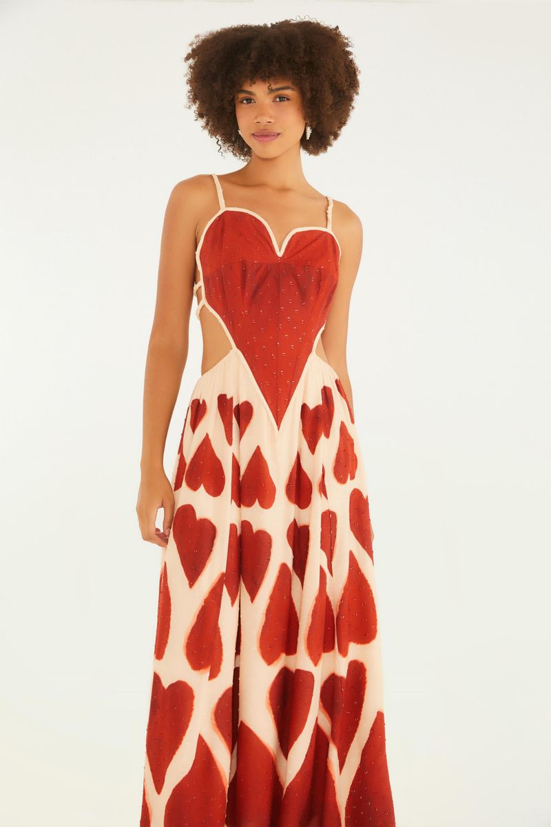 Vista lateral del vestido maxi con estampado de corazones rojos, destacando el corte fluido y tirantes finos.