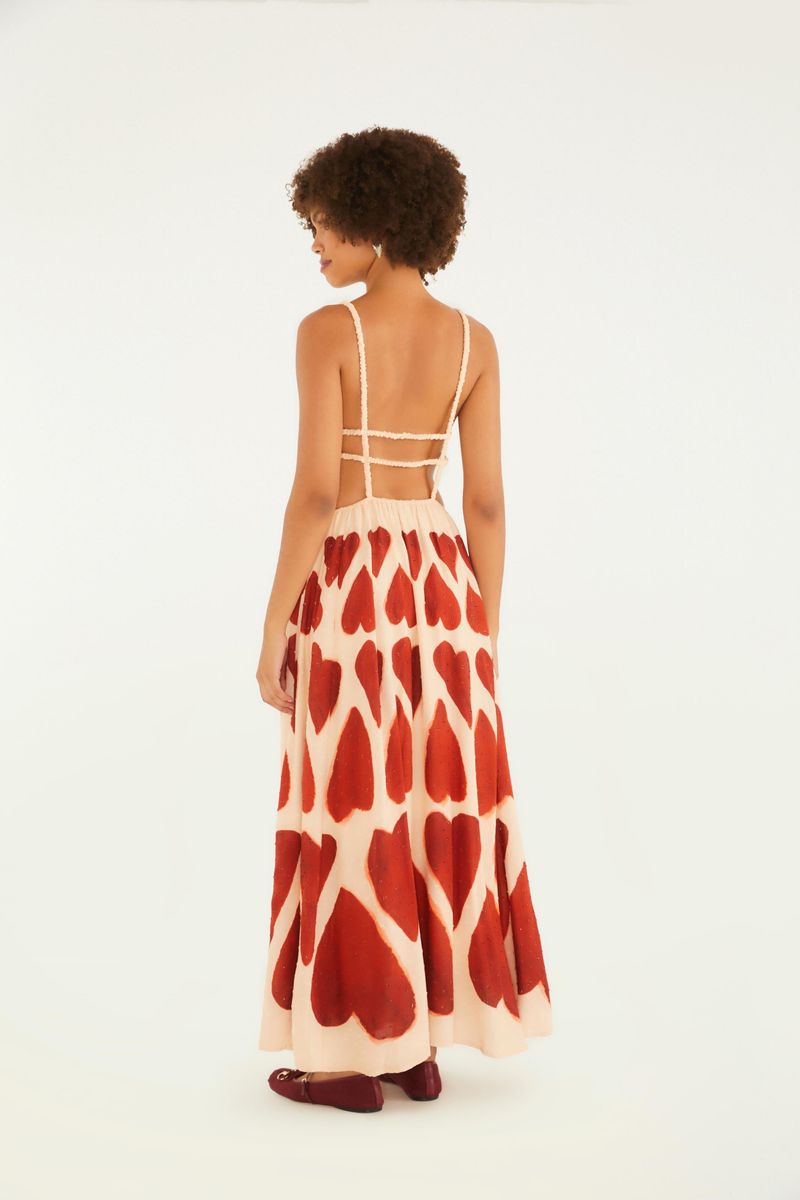Vista trasera del vestido maxi con estampado de corazones rojos, destacando los tirantes finos y el corte fluido.