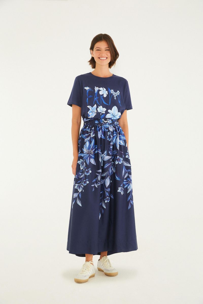 Modelo usando camiseta azul oscuro con estampado floral, combinada con falda larga.