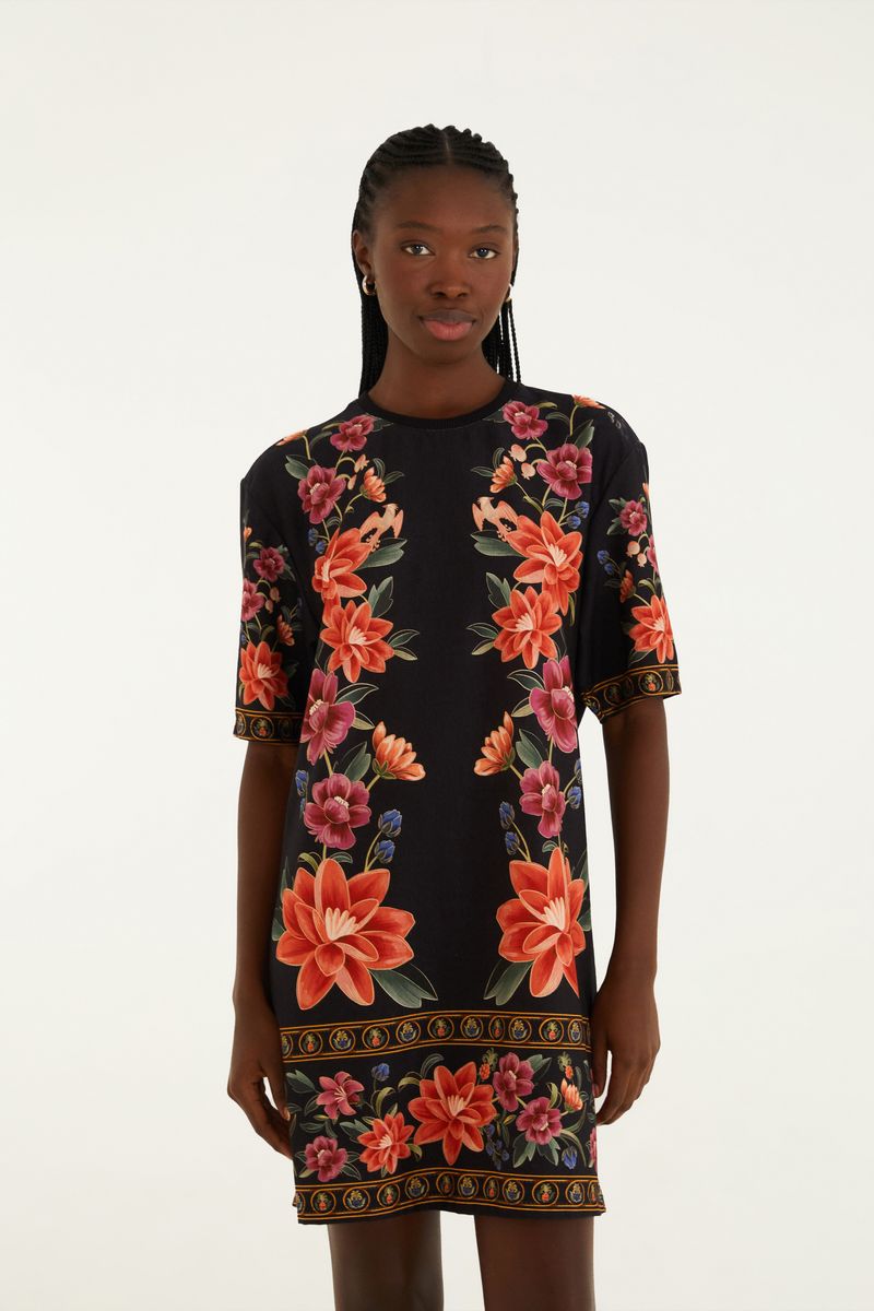 Vestido tipo camiseta con estampado floral vibrante sobre fondo negro, vista frontal.