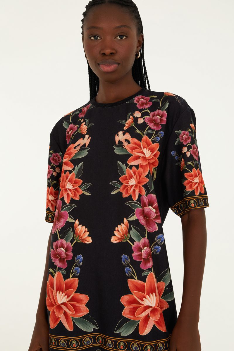 Vestido tipo camiseta con estampado floral vibrante sobre fondo negro, vista lateral.