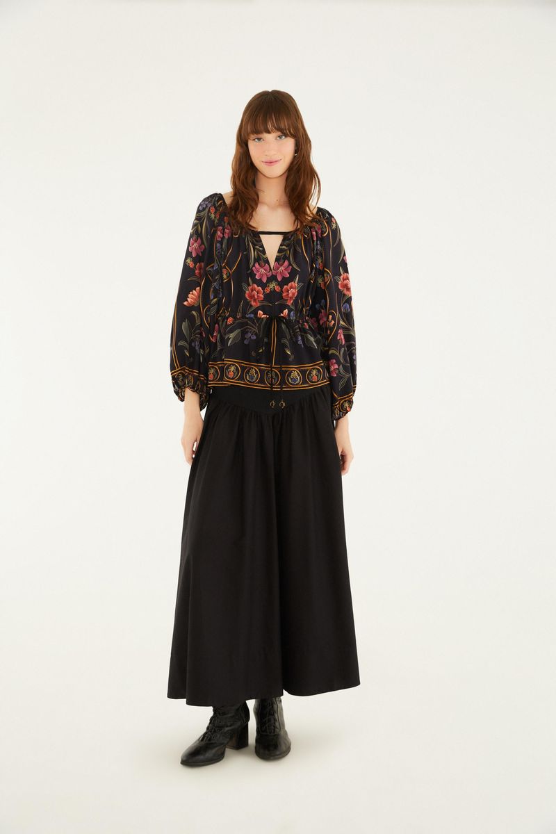 Modelo vistiendo blusa floral con falda negra en una pose completa.