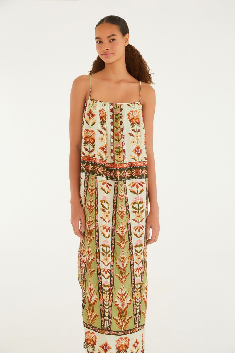 Imagen de un vestido estampado con tirantes finos, visto de espaldas, con detalles florales y geométricos en tonos de verde, naranja y blanco.
