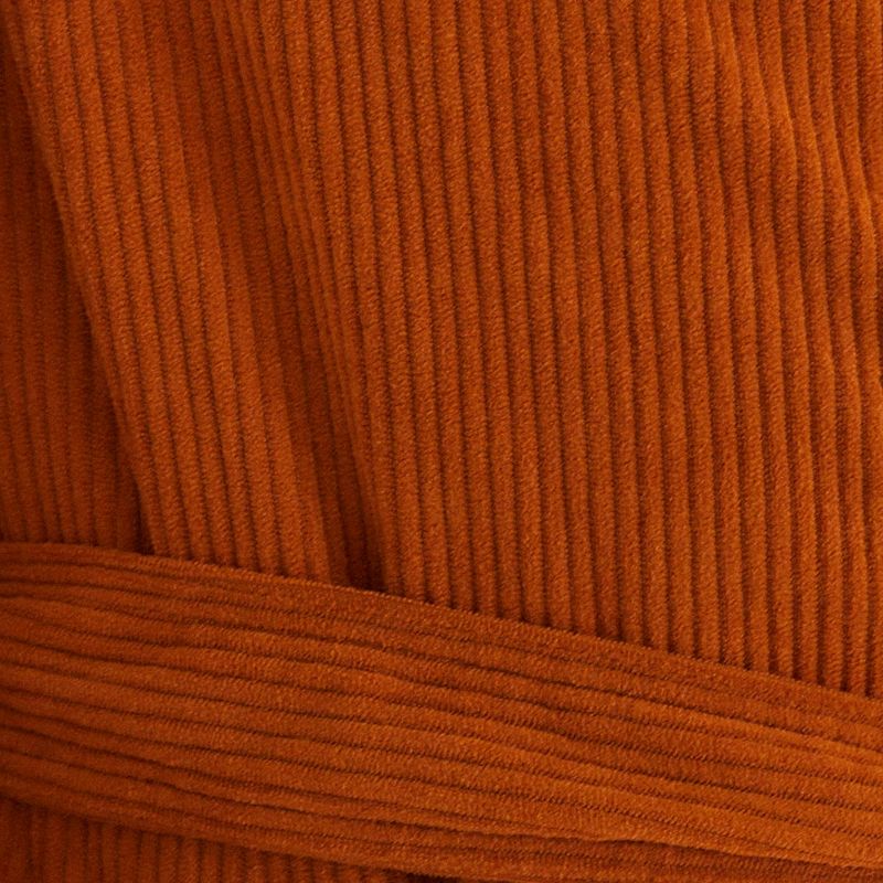 Detalle del tejido de velour corduroy marrón del trench coat.