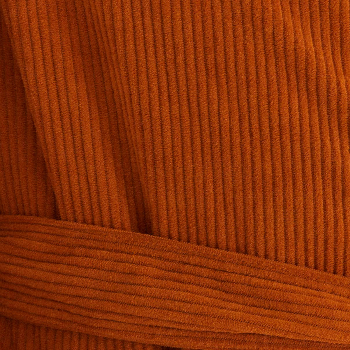 Detalle del tejido de velour corduroy marrón del trench coat.