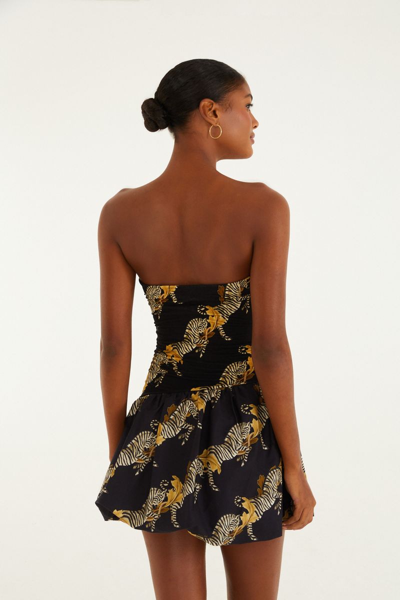 Vista trasera del vestido corto con estampado de cebra sobre fondo negro.