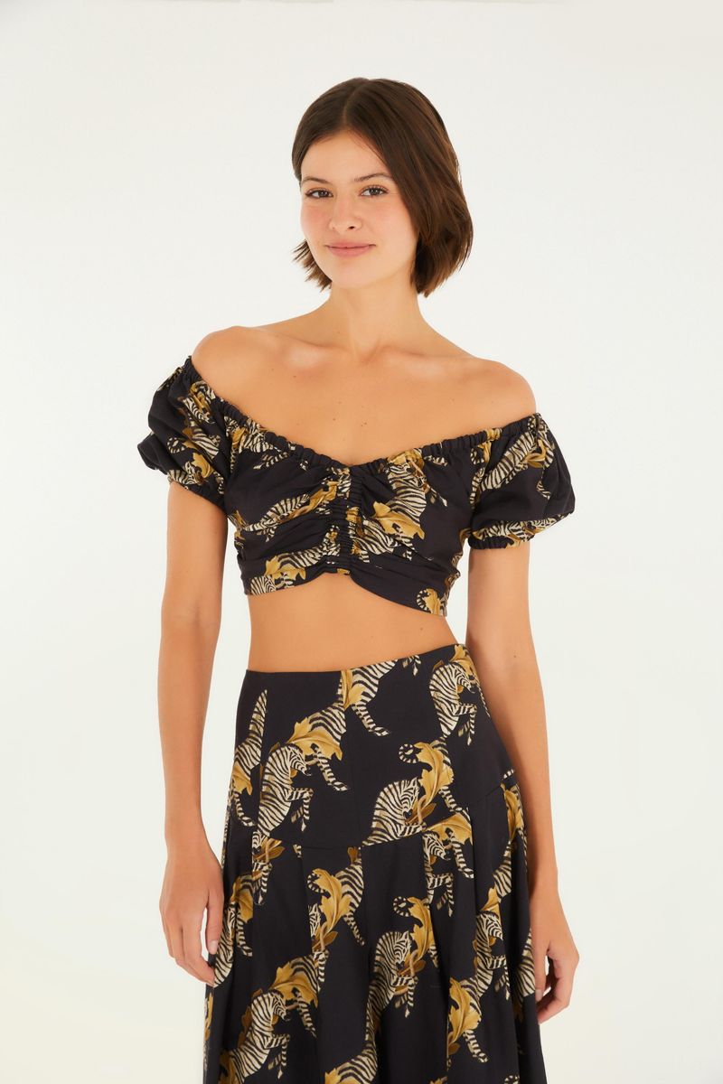 Blusa estampada con tema de cebra, vista frontal mostrando el escote hombro a hombro y mangas abullonadas.