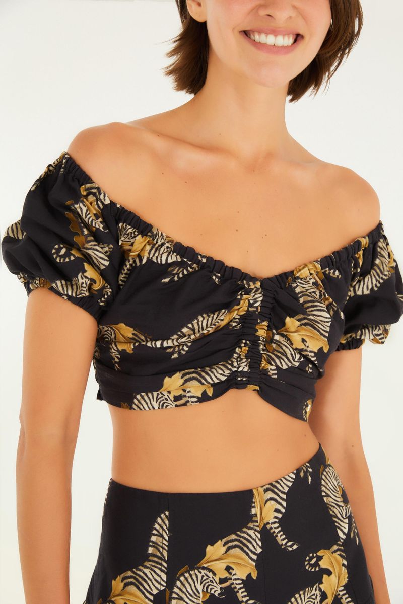 Detalle del escote hombro a hombro y mangas abullonadas de la blusa estampada con tema de cebra.
