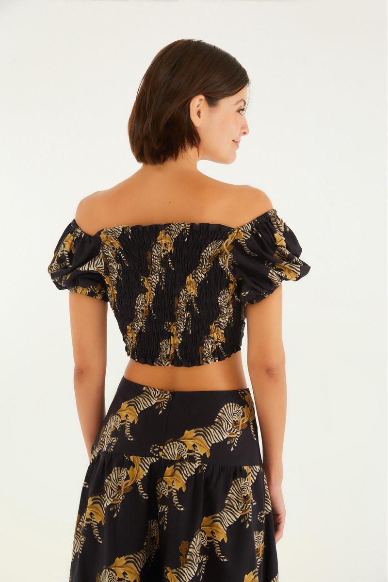 Vista lateral de la blusa estampada con tema de cebra, mostrando el ajuste y el estilo corto.
