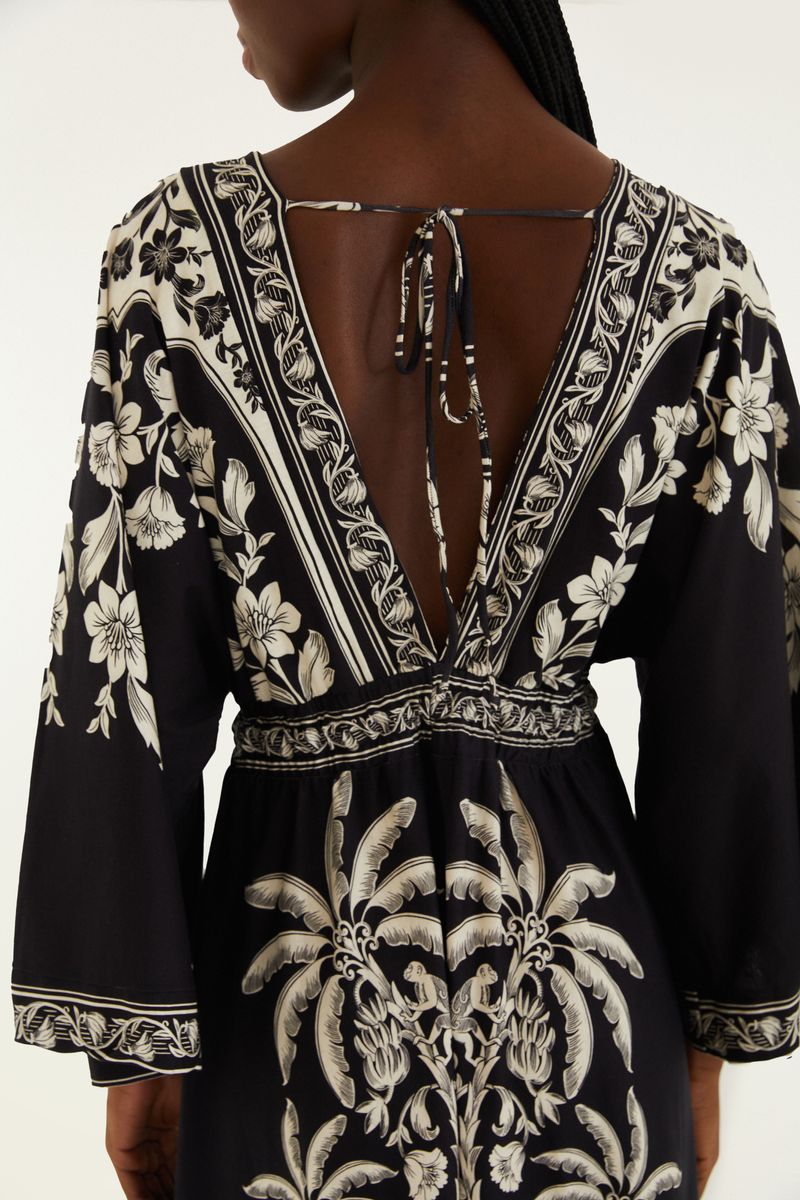 Detalle de la espalda del vestido midi negro con estampado floral blanco, mostrando el escote profundo y la amarra.
