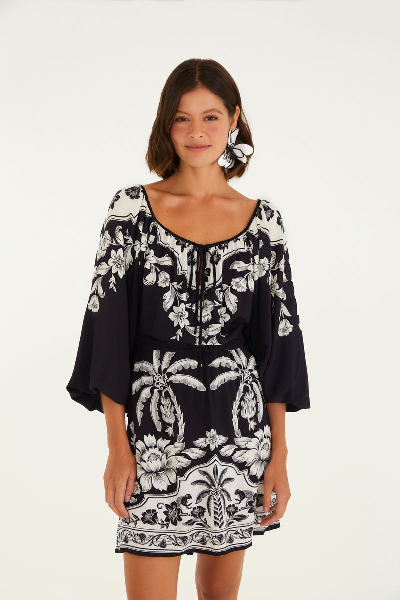 Vestido corto con diseño floral en negro y blanco, cuello redondo y mangas largas.