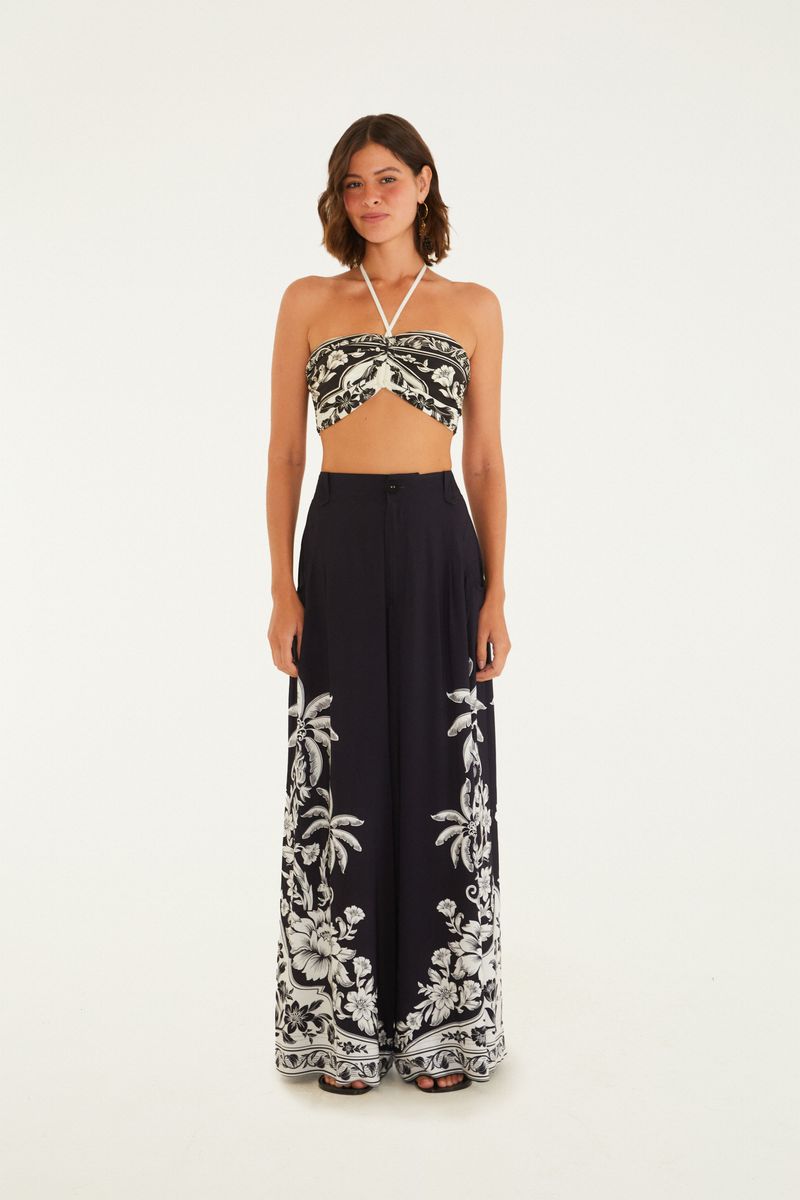 Vista frontal de un pantalón ancho negro con estampado tropical en blanco.