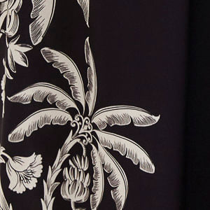 Detalle del borde del pantalón ancho negro con estampado tropical en blanco.