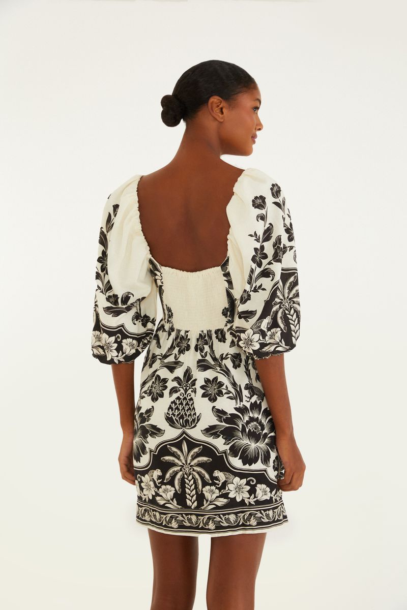 Vista lateral del vestido corto con estampado floral en blanco y negro, destacando las mangas abullonadas.