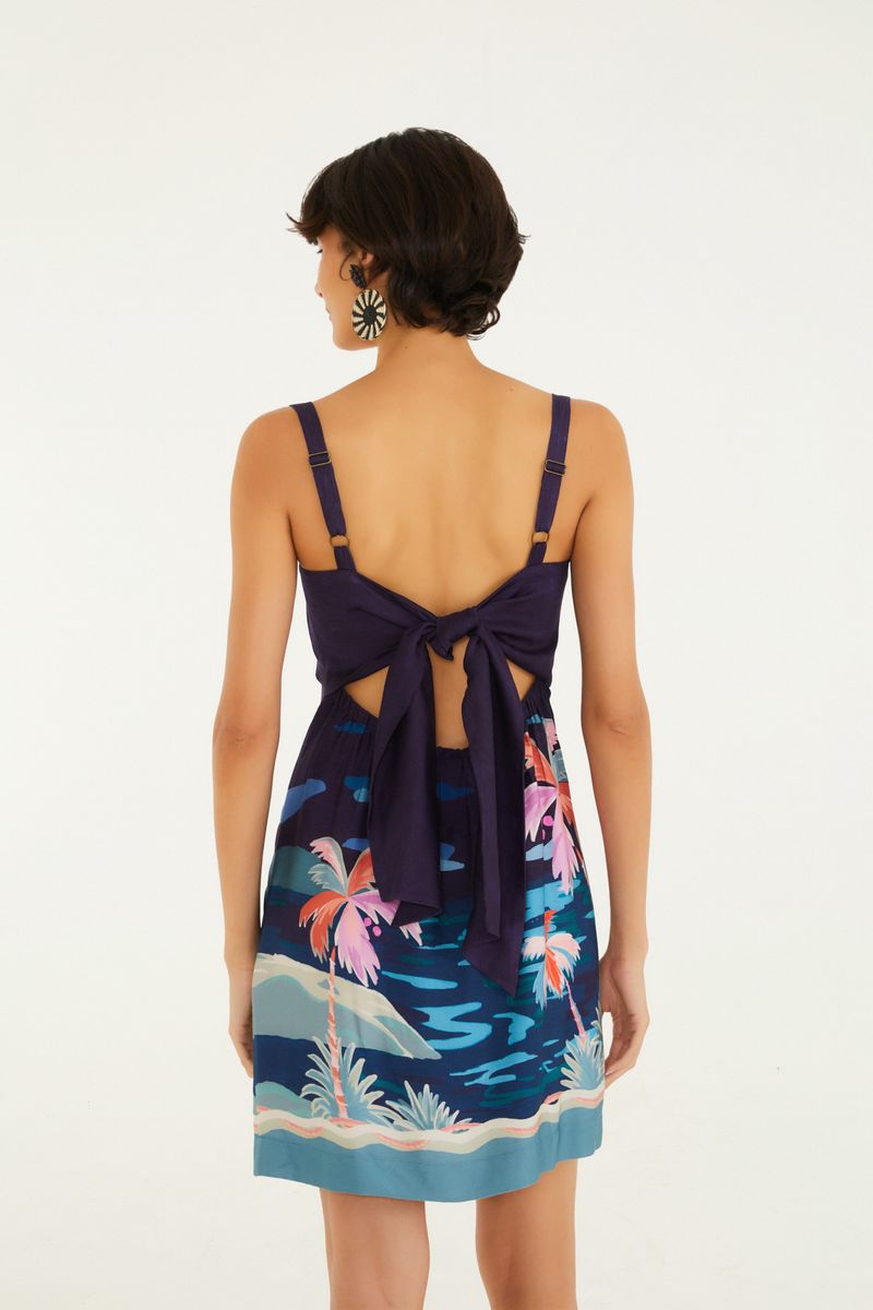 Imagen de un vestido corto con tirantes anchos y estampado tropical, visto desde atrás, con detalle de amarre.