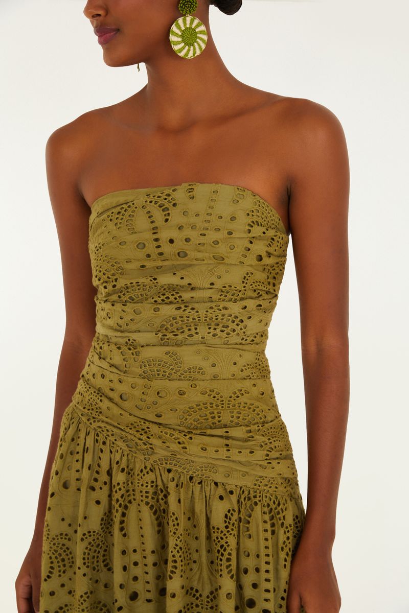 Acercamiento al escote palabra de honor del vestido verde con detalles de laise.