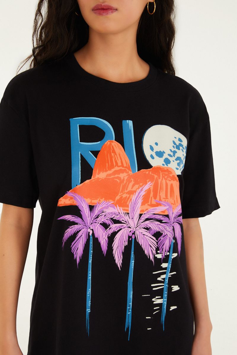 Primer plano del estampado tropical en la camiseta negra, destacando palmeras y montañas.