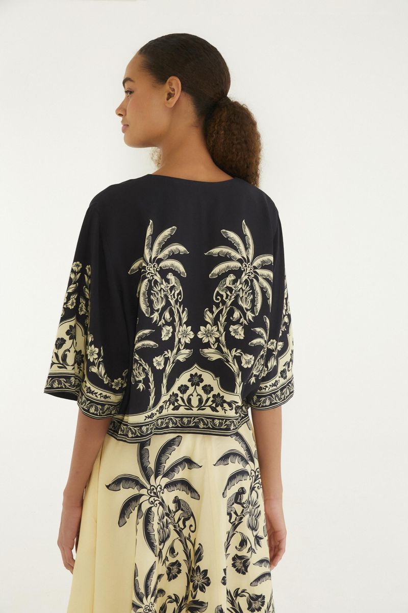 Vista trasera de la camiseta cropped con estampado botánico en negro y beige.