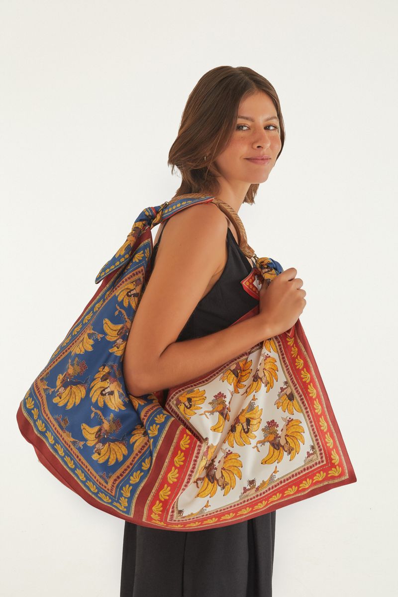 Modelo sosteniendo la Bolsa Mini Sereia Banana con estampados vibrantes.