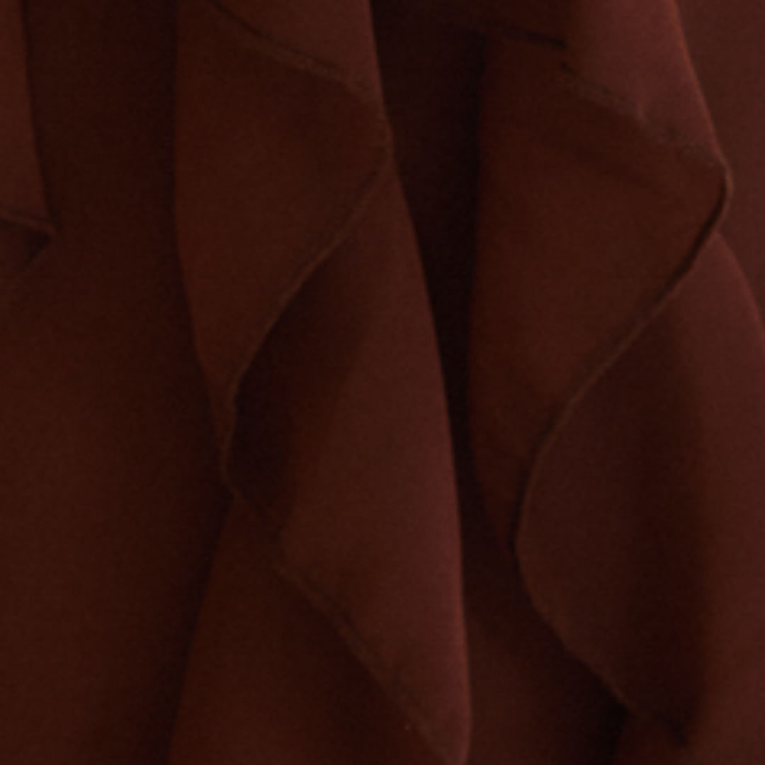 Detalle ampliado de la tela del vestido largo marrón, destacando la textura y calidad.
