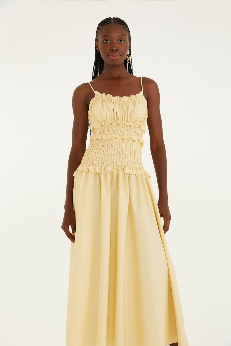 Vestido amarillo con lastex y tirantes delgados, visto de lado.