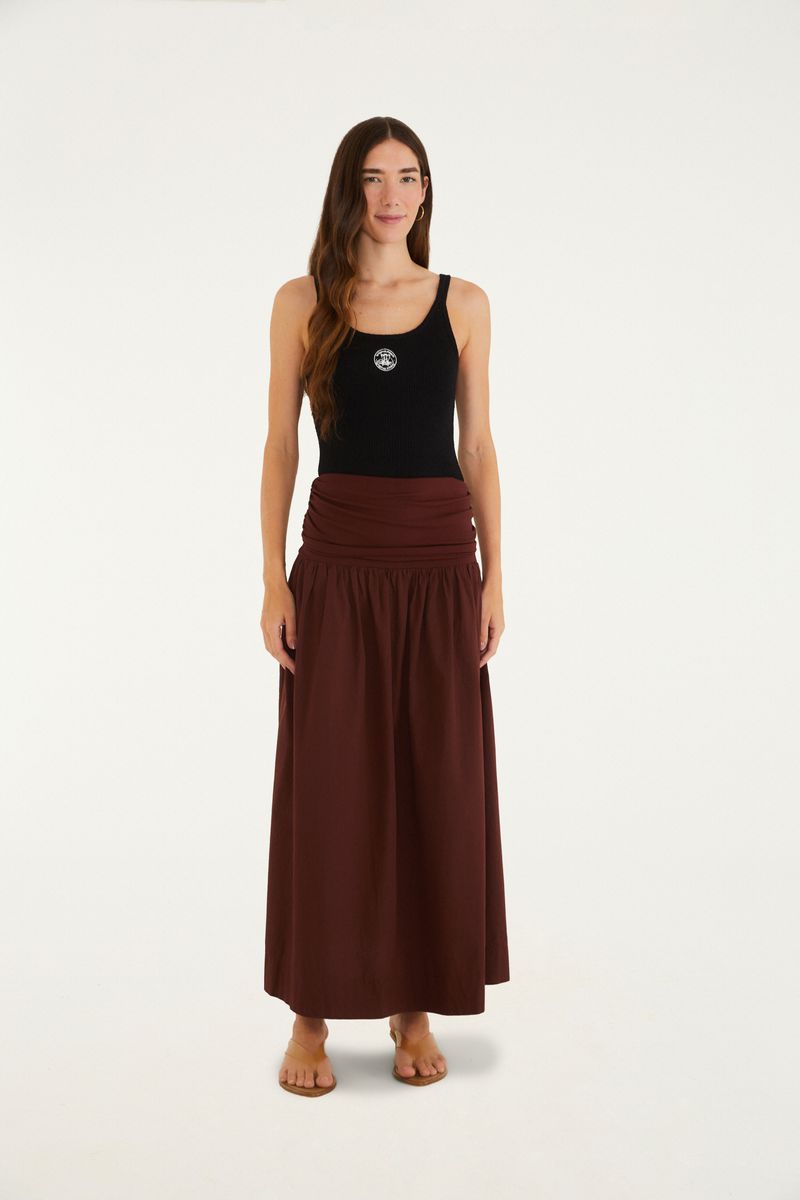 Modelo usando una falda larga marrón con detalle fruncido y blusa negra.