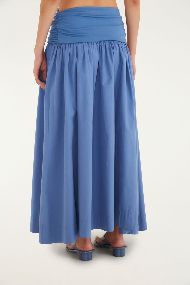 Imagen de una falda larga azul con gala fruncida, combinada con una camiseta blanca.