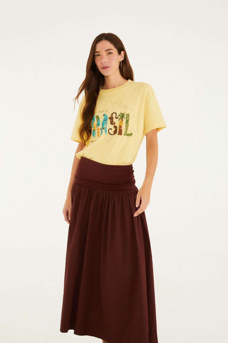 Modelo usando una falda larga marrón con detalle fruncido y camiseta amarilla.