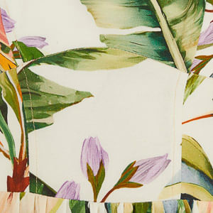 Acercamiento del estampado tropical del vestido corto, mostrando detalles de hojas y flores.