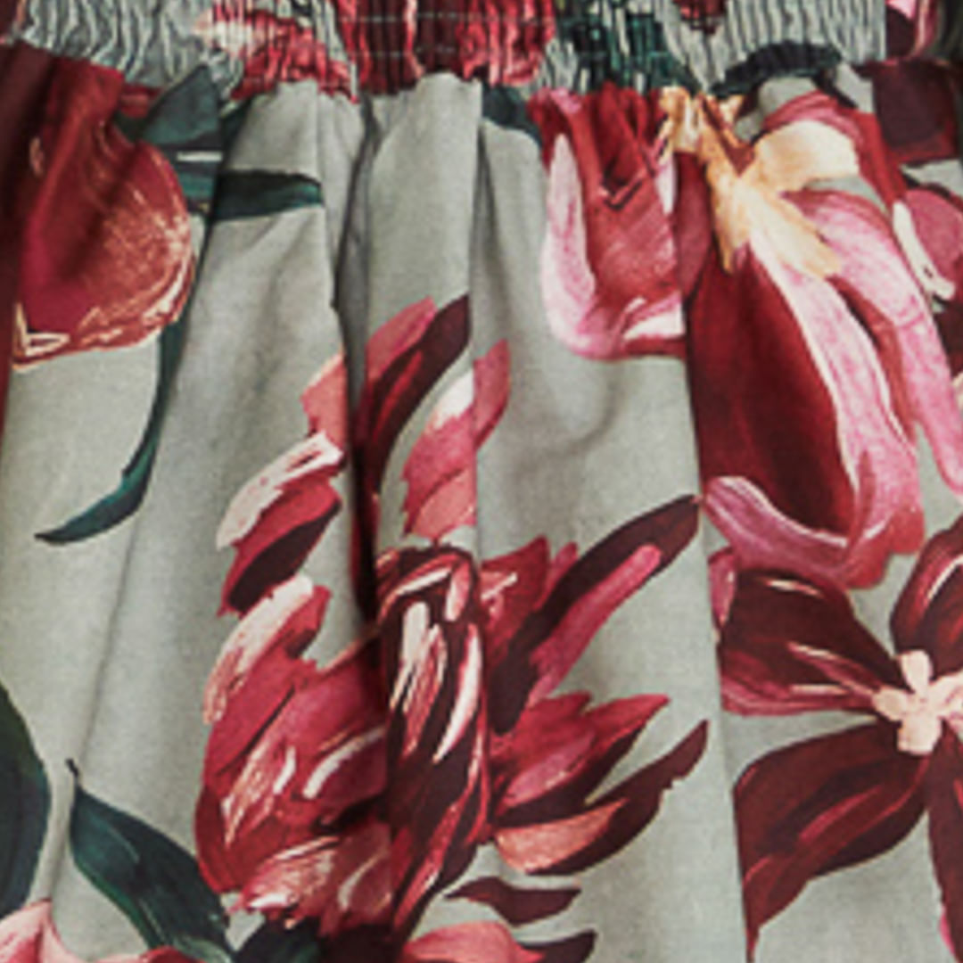 Primer plano del estampado floral en tonos rojo y verde del vestido corto.