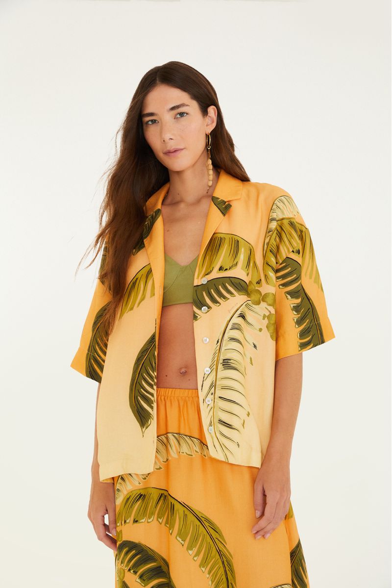 Camisa tropical con estampado de palmeras en tonos naranja y verde, vista frontal.