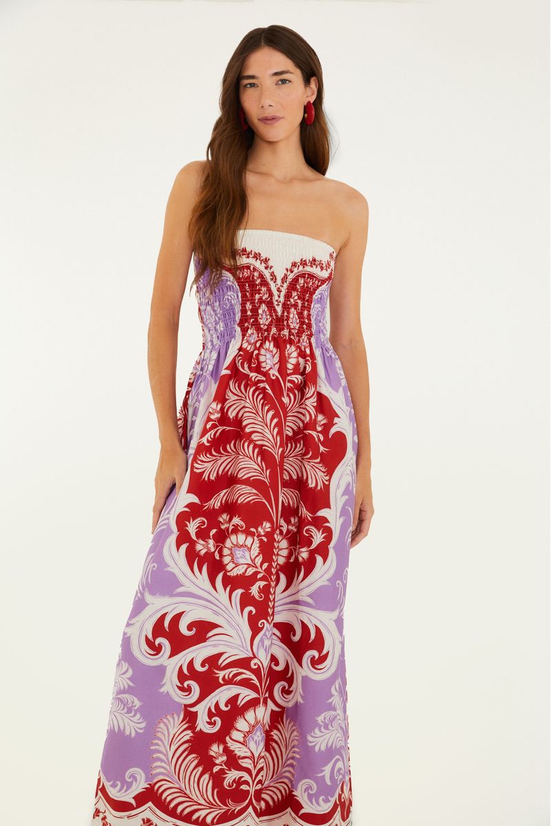 Vestido midi estampado con diseño floral y botánico en tonos de rojo y lila, visto de lado.