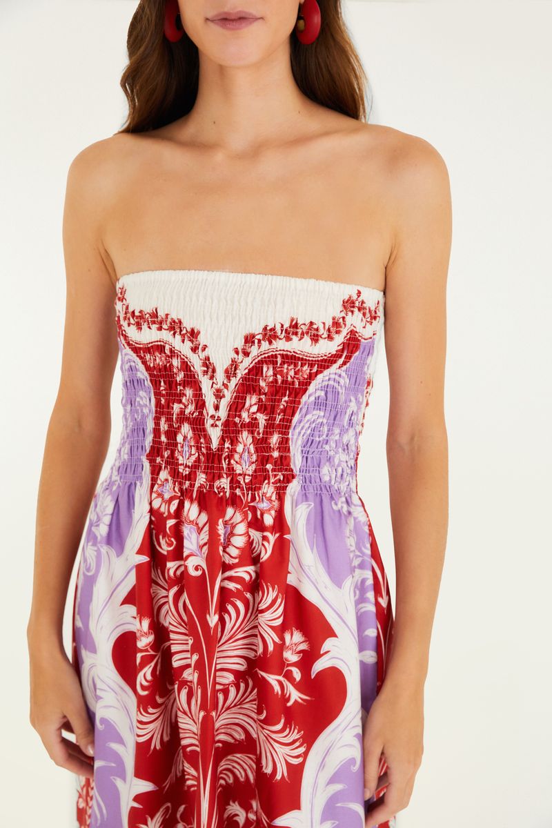 Vestido midi estampado con diseño floral y botánico en tonos de rojo y lila, visto de espaldas.