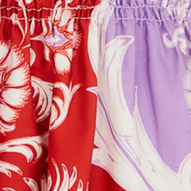 Detalle de la falda del vestido midi estampado con diseño floral y botánico en tonos de rojo y lila.