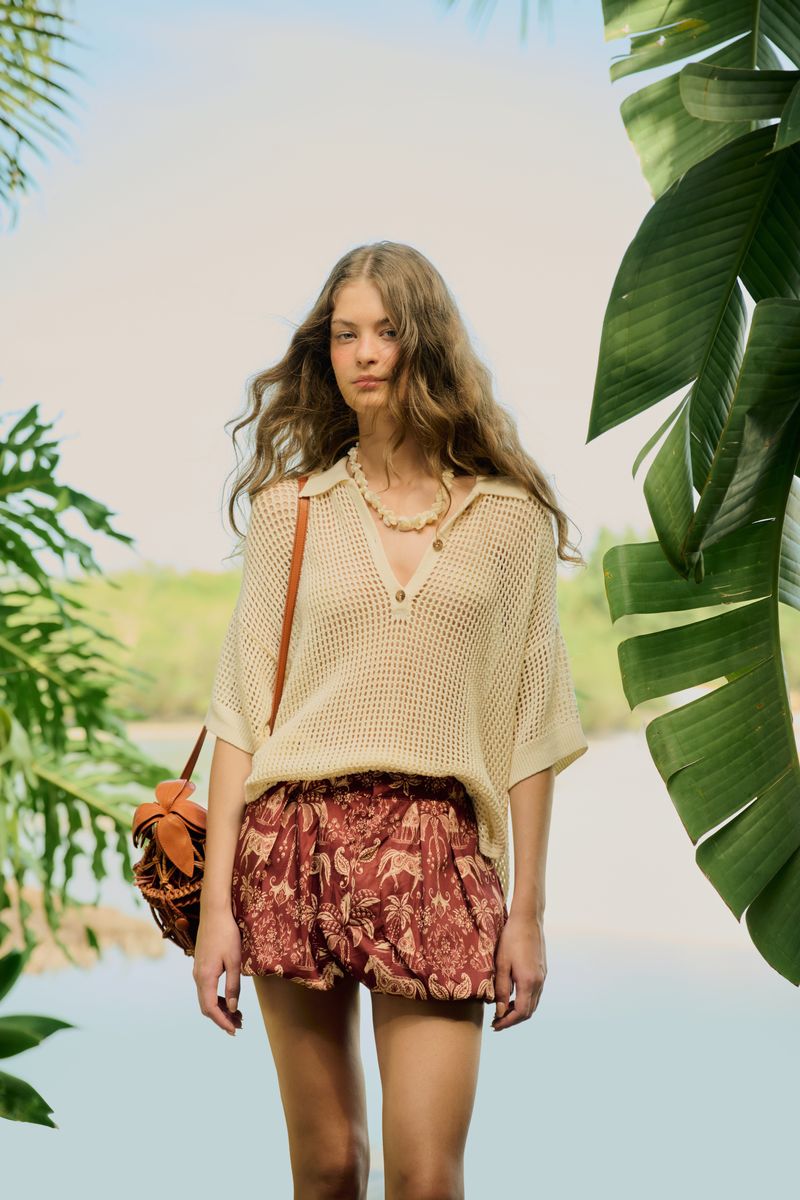 Blusa Polo Tricot Telado en entorno tropical, combinada con pantalones cortos estampados.