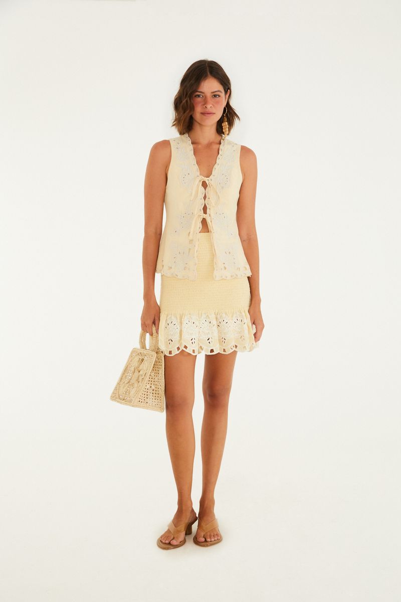 Imagen completa de una modelo usando el chaleco bordado artesanal beige, combinado con una falda.