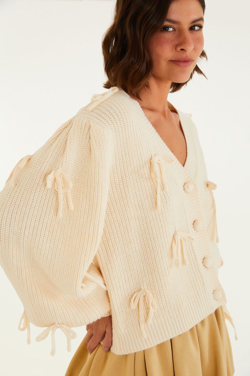 Detalle de las mangas abultadas del cárdigan de tricot beige.