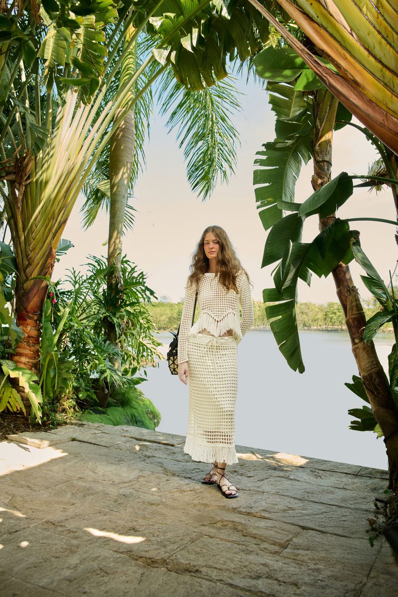 Modelo usando un pantalón tejido beige en un ambiente tropical.