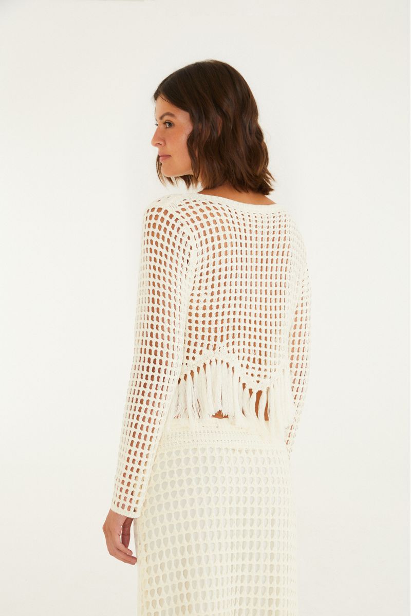Vista trasera de la blusa de tejido beige con flecos, mostrando el diseño completo.
