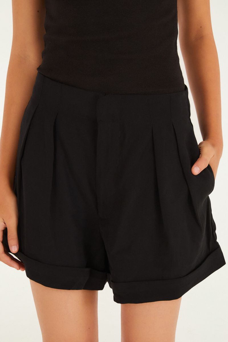 Detalle del short de sastrería negro mostrando los bolsillos y el dobladillo doblado.