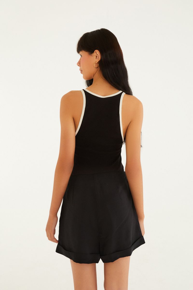 Modelo usando un short de sastrería negro con blusa negra, vista trasera.