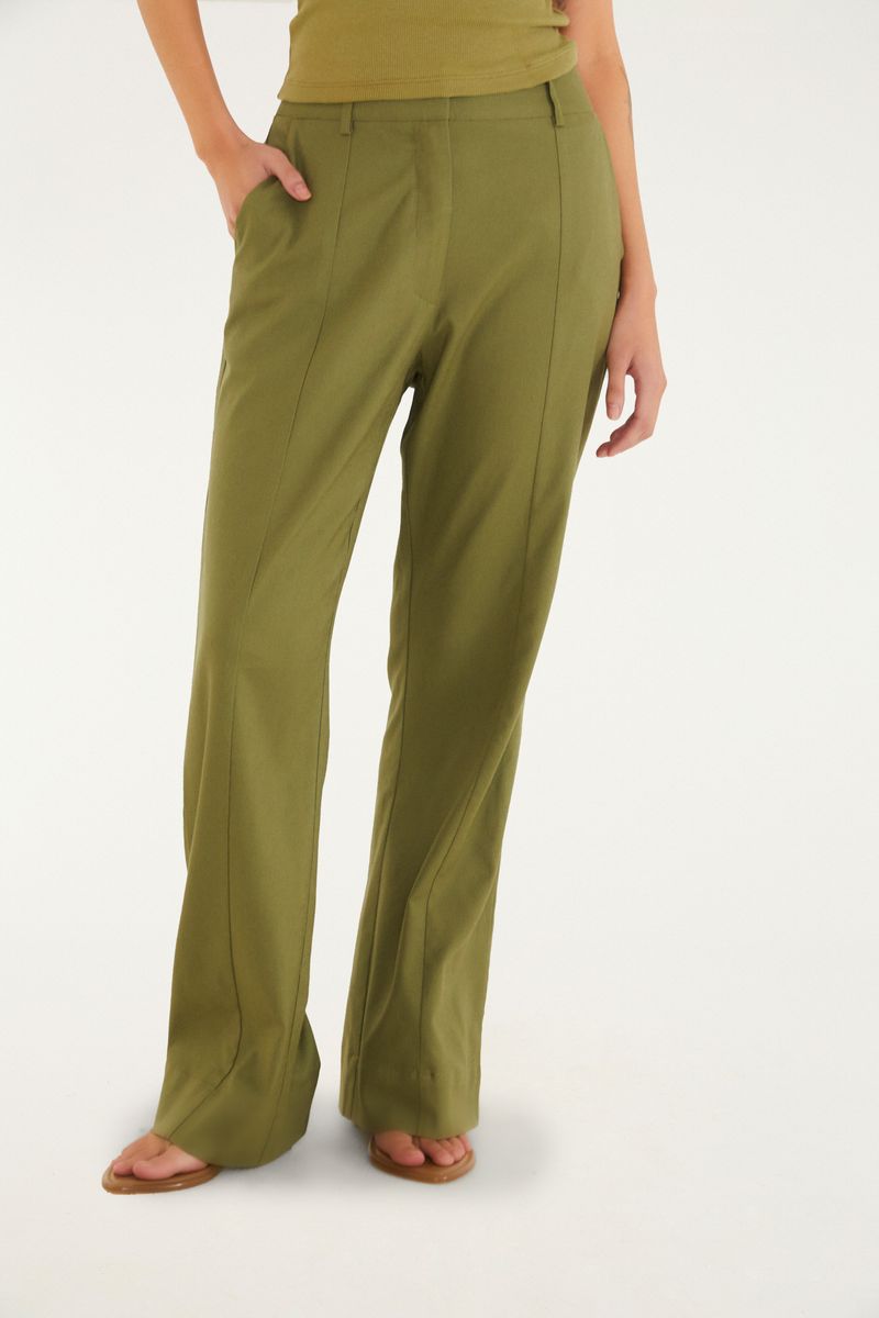 Detalle de la pretina alta y limpia del pantalón de sastrería verde.