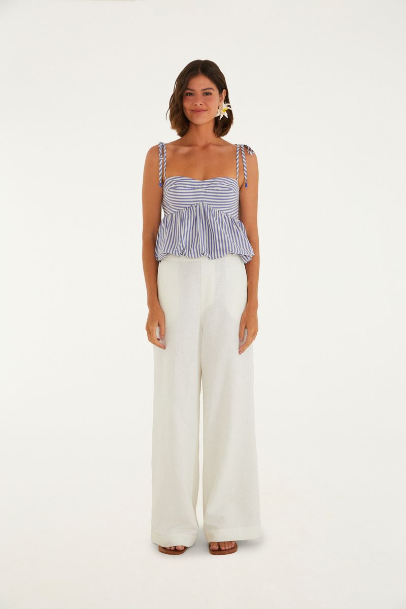 Modelo vistiendo pantalón amplio de sastrería beige con top rayado azul y blanco.
